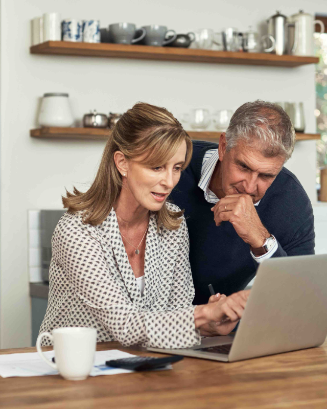 Couple reviewing finances at a kitchen laptop